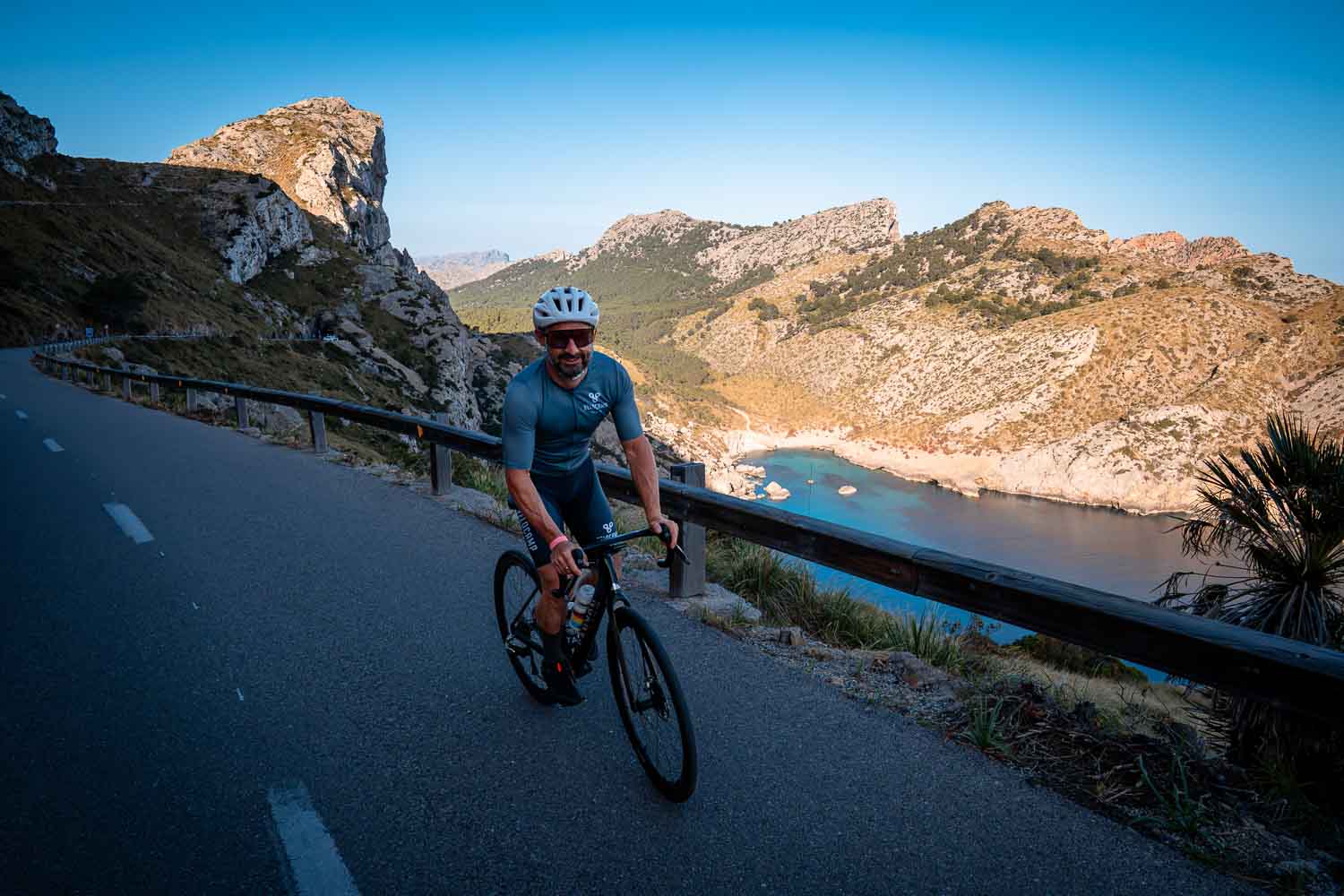 Smiling cyclist blue water behind