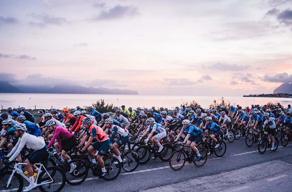 Mass start at Platja de Muro at dawn with thousands of riders rolling out together]