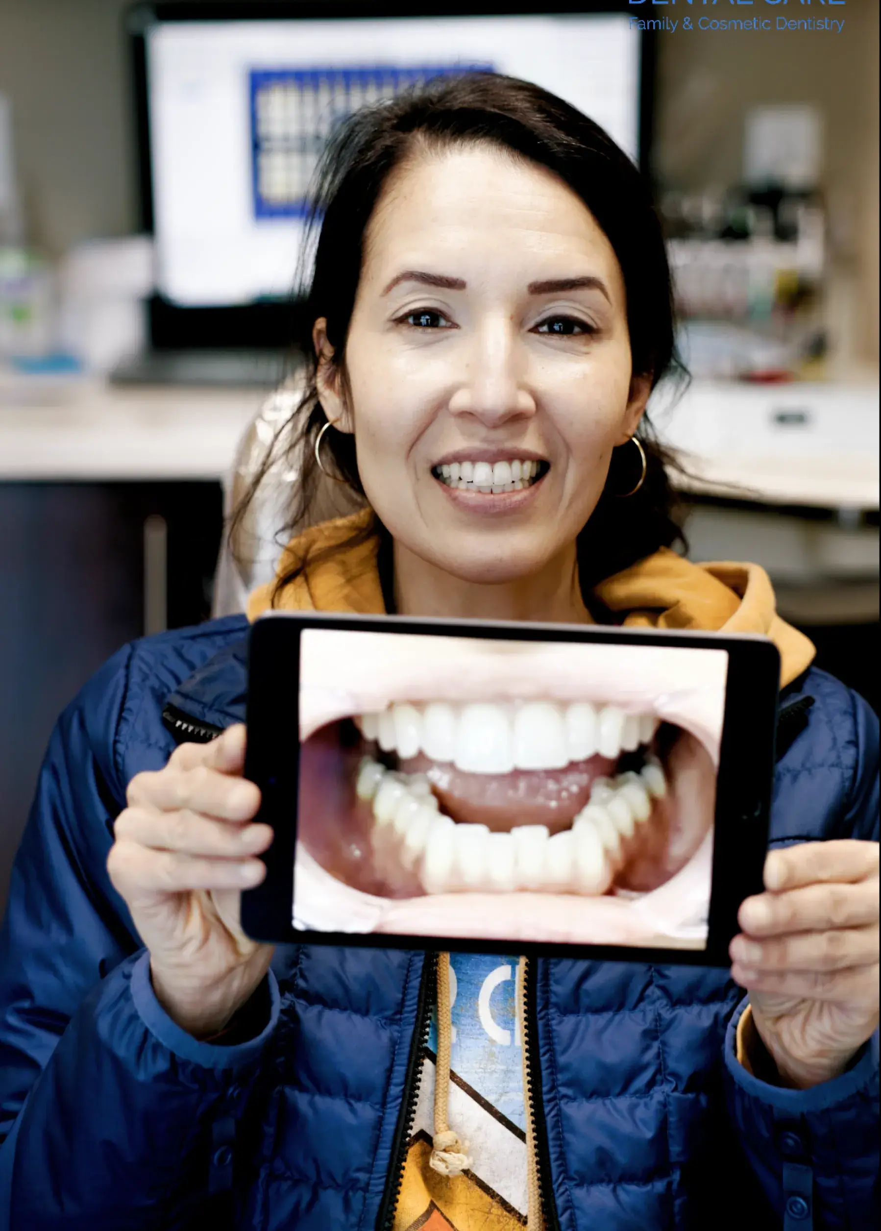 A woman smiling holding a picture of her previous smile.