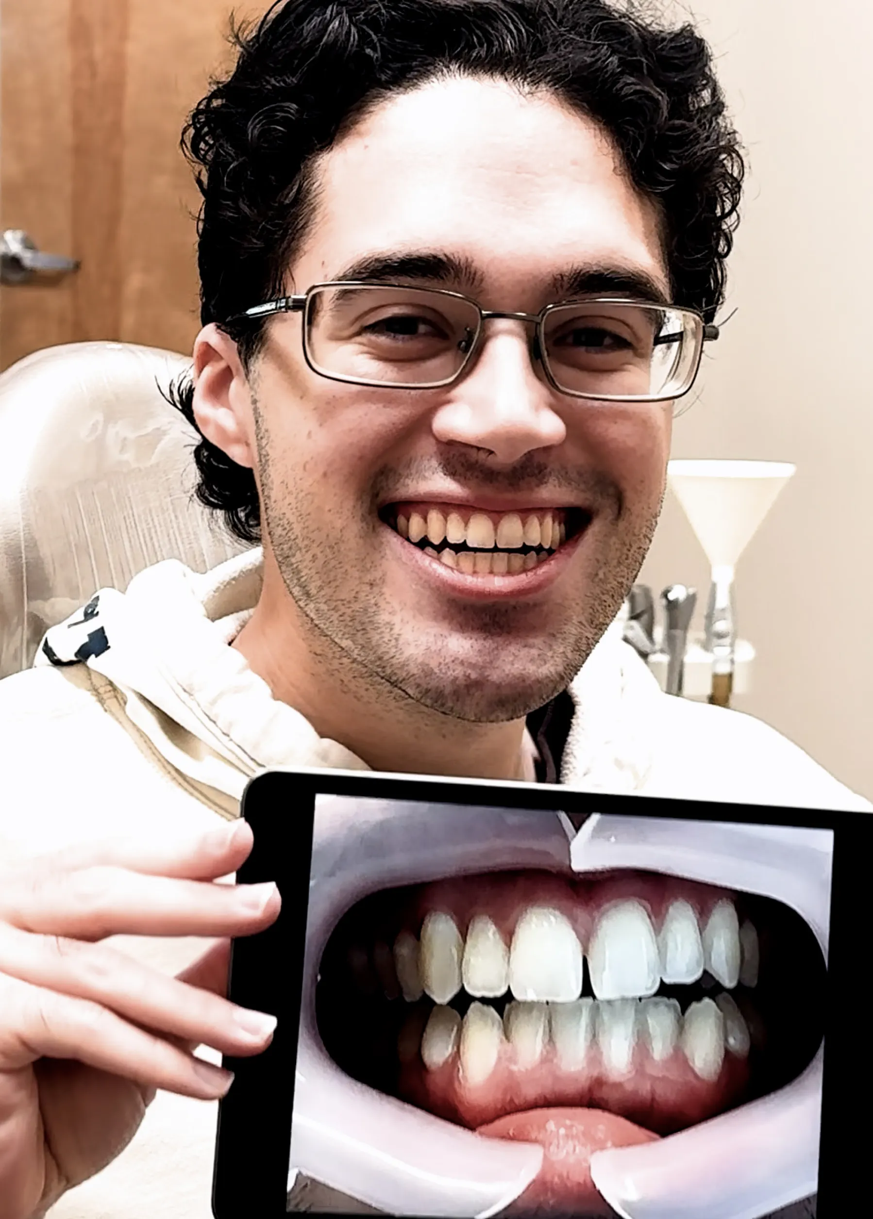 A man smiling holding a picture of his previous smile.