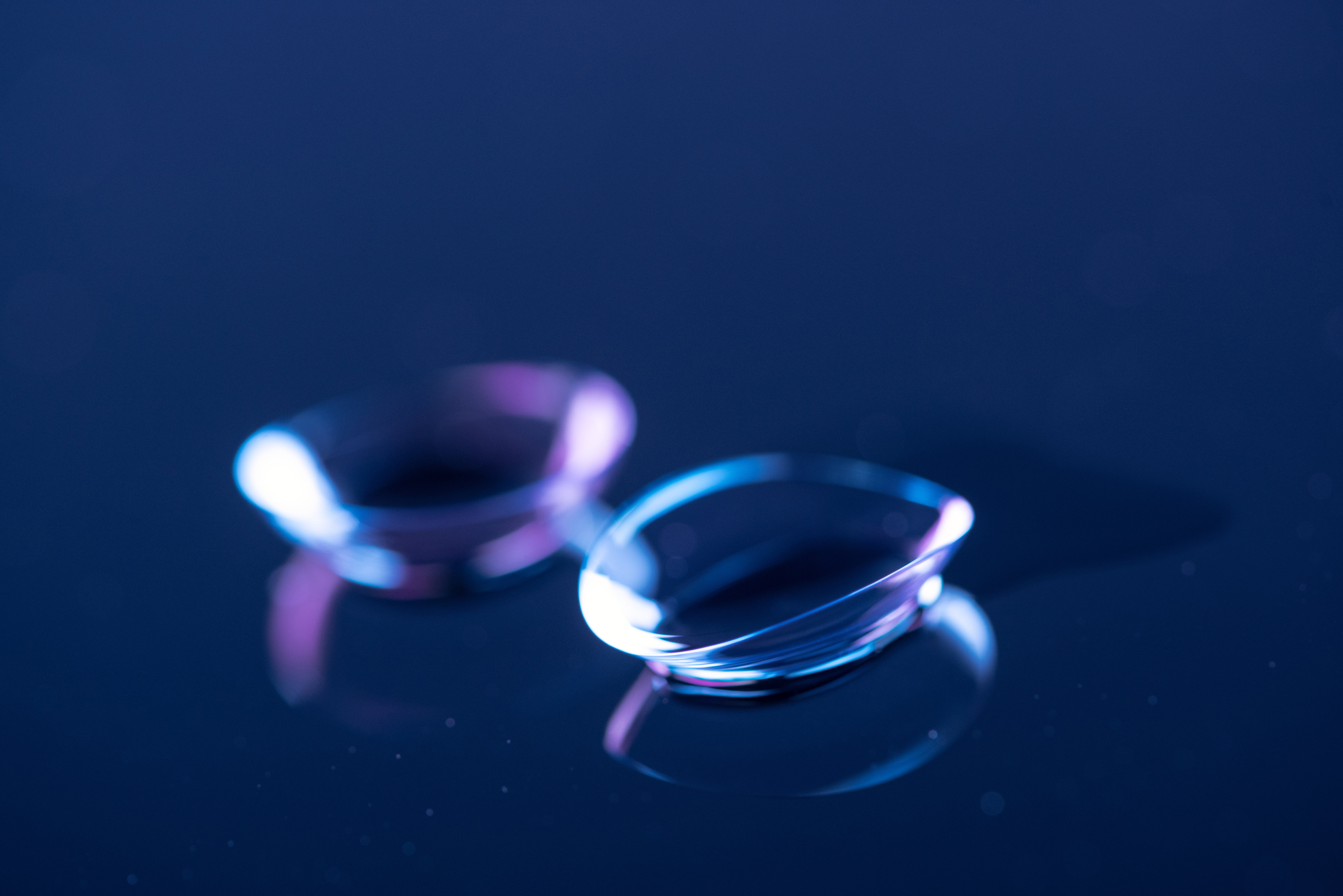 Contact lenses with blue and purple reflections on dark background