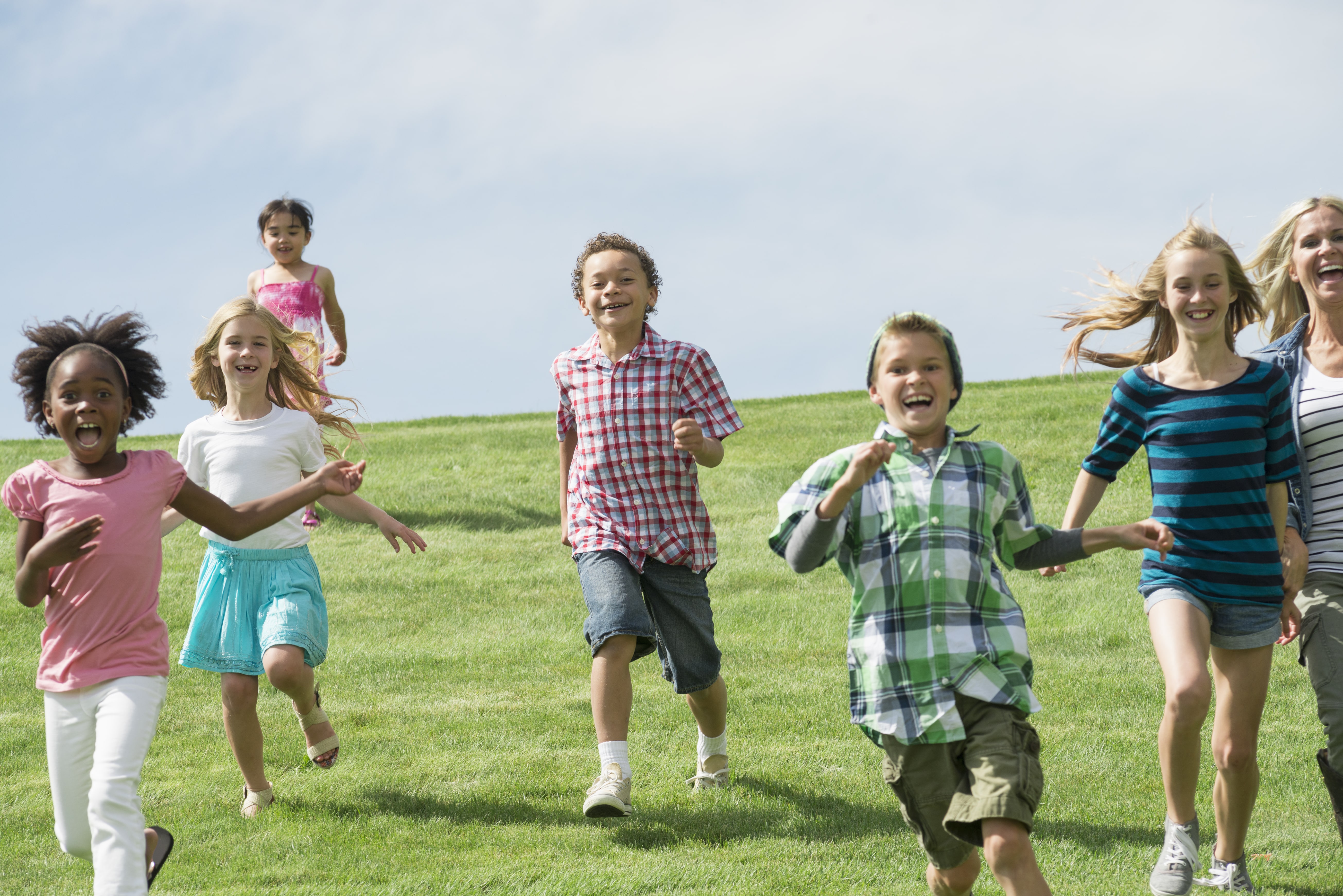 Diverse group of children running and playing together on a grassy field