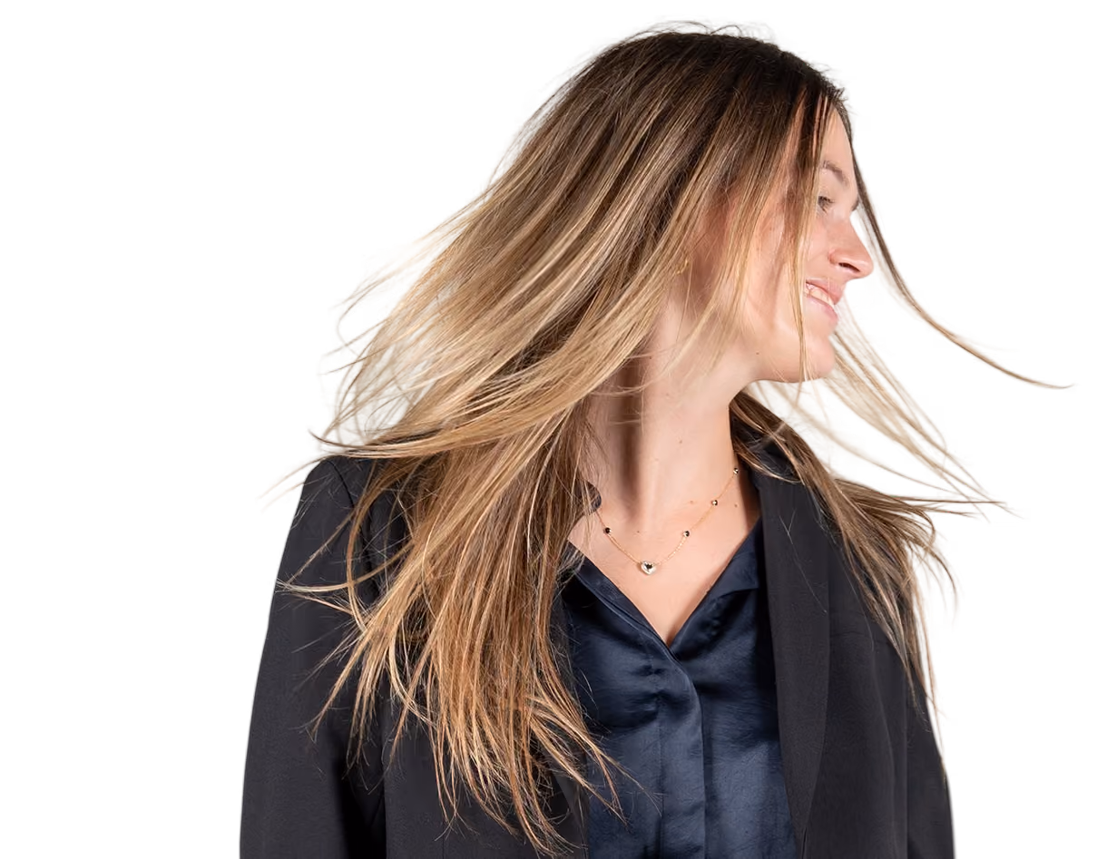 Smiling woman with long blonde hair wearing a black blazer and navy blouse, head turned right.