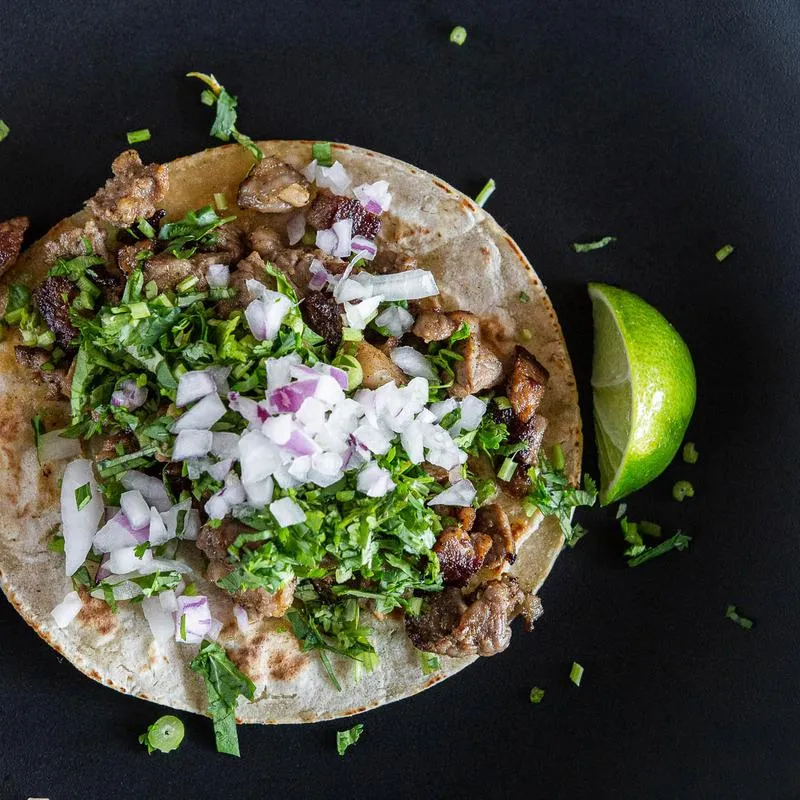 A steak taco with onion, cilantro and lemon slide 