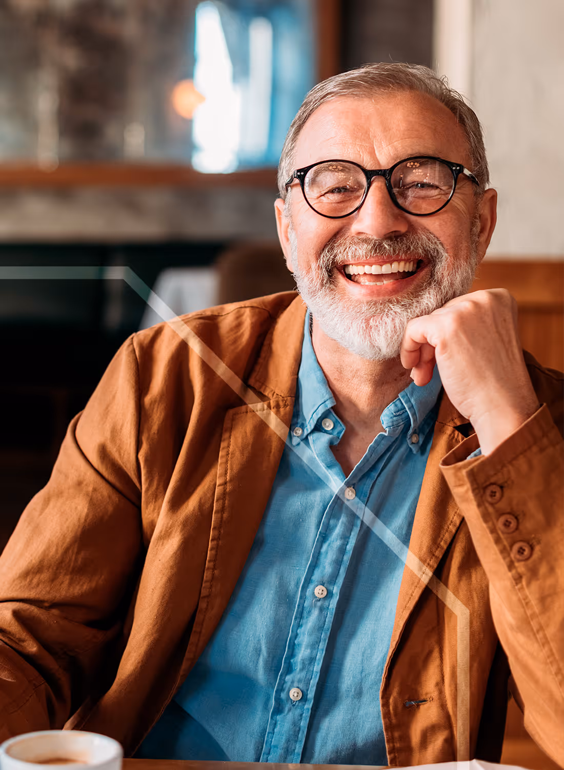 Homme souriant après un traitement en implantologie, assis dans un café, confiant et détendu