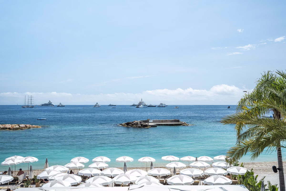 Larvotto beach in Monaco under a clear blue sky, with sea and umbrellas