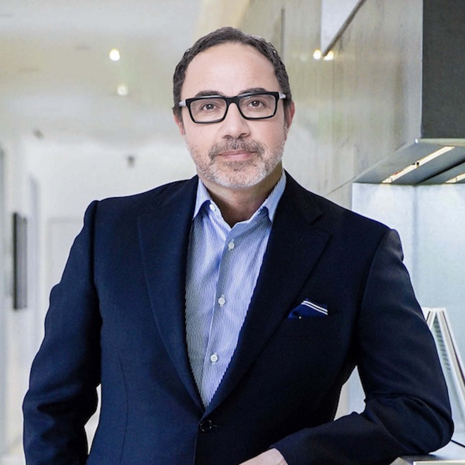 Dr. David Amron standing in a hallway at The ROxbury Institute, wearing a sharp dark suit and glasses