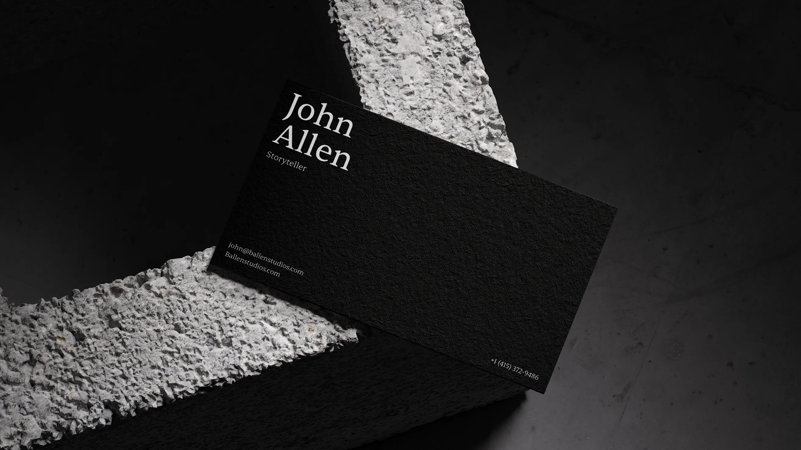 Textured black business card design for John Allen (MrBallen), featuring the new logo and contact details, displayed on a raw concrete surface