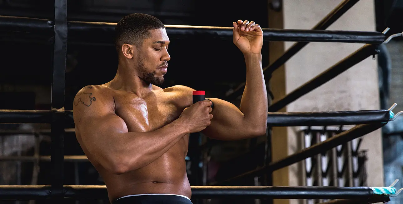 Lifestyle photography showing Anthony Joshua using the Pulseroll massage gun on his bicep for muscle recovery