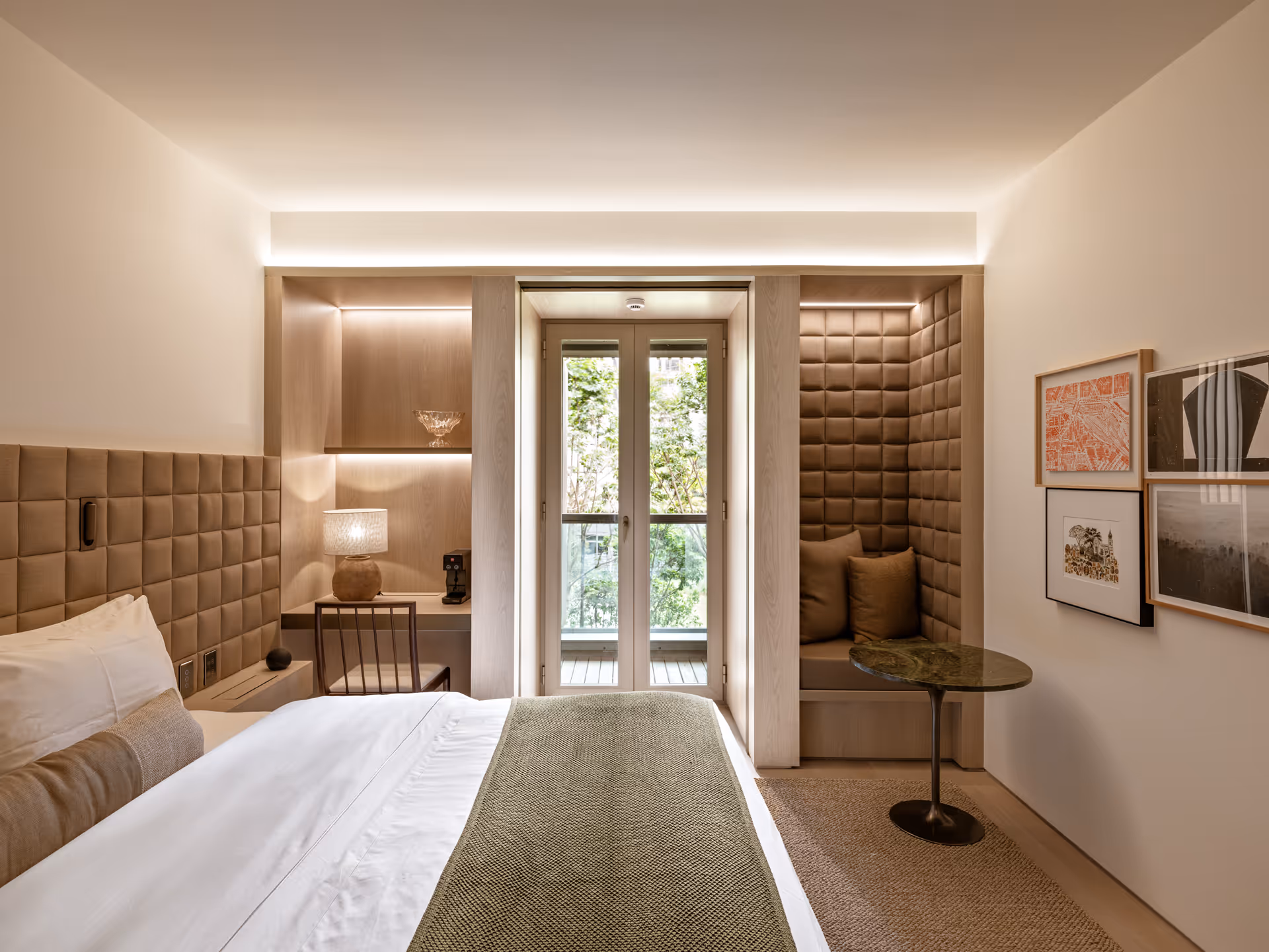 Cozy hotel room with city view balcony seating and warm brown accents.