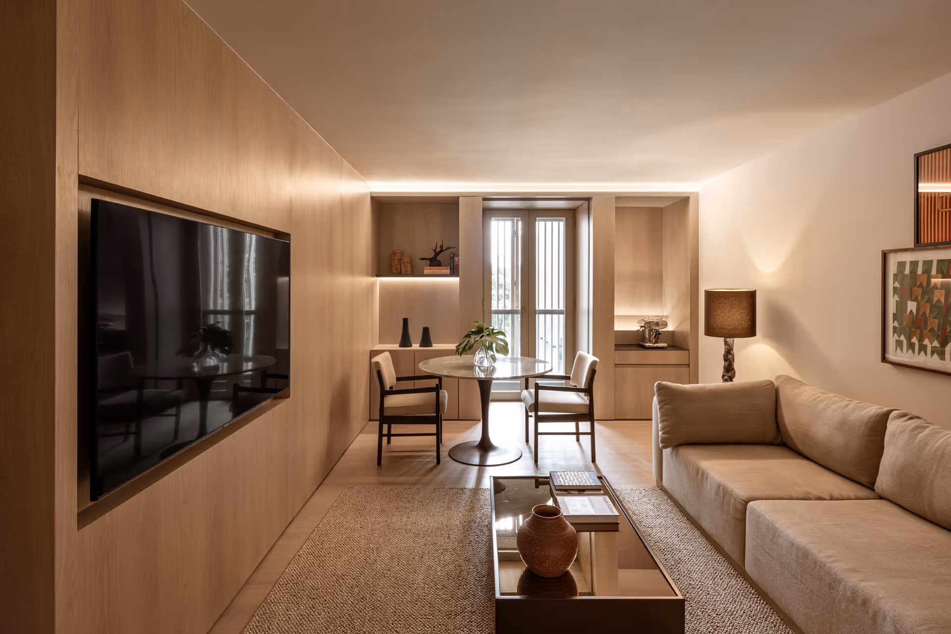 Cozy modern living room with beige couch, sleek wall-mounted TV, and stylish dining space.