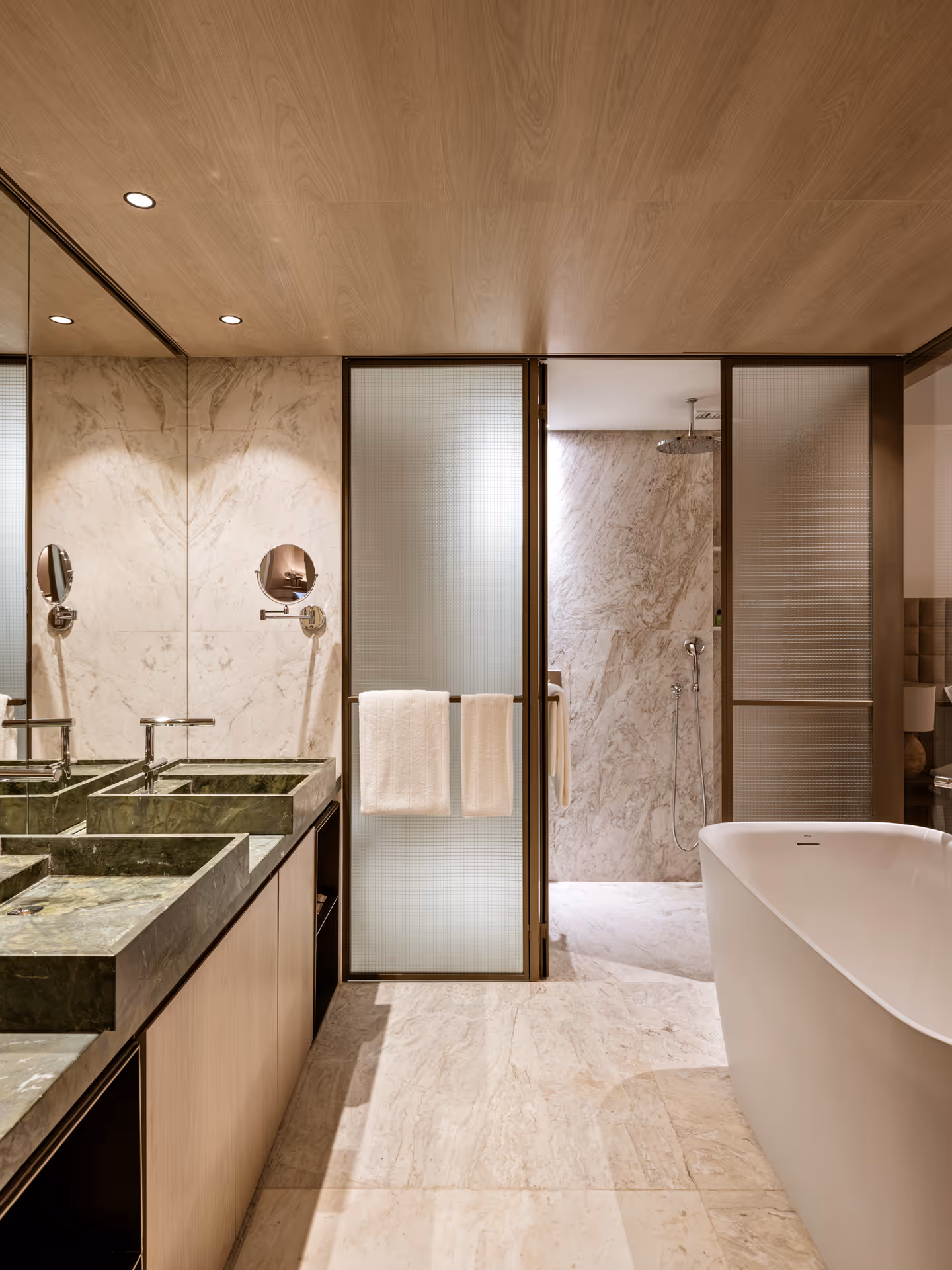 Luxury modern bathroom features freestanding tub, double sink, and marble walled shower area.