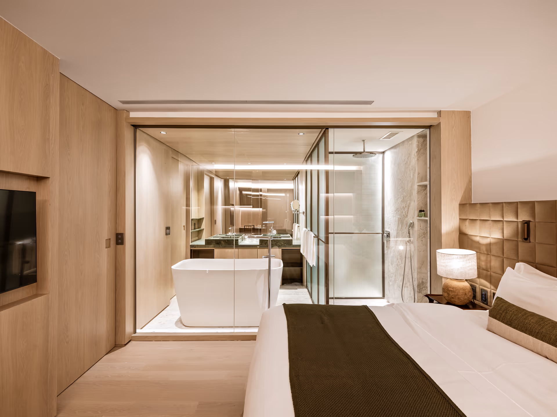 Luxurious modern hotel room features sleek bathroom, bathtub, and glass door amenities freely.