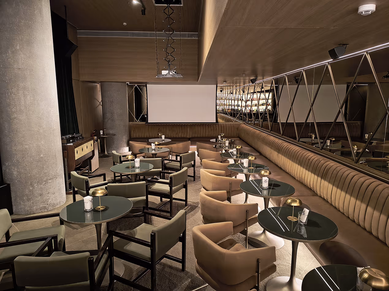 Modern lounge interior design features beige seating, round tables, and geometric mirrored walls.