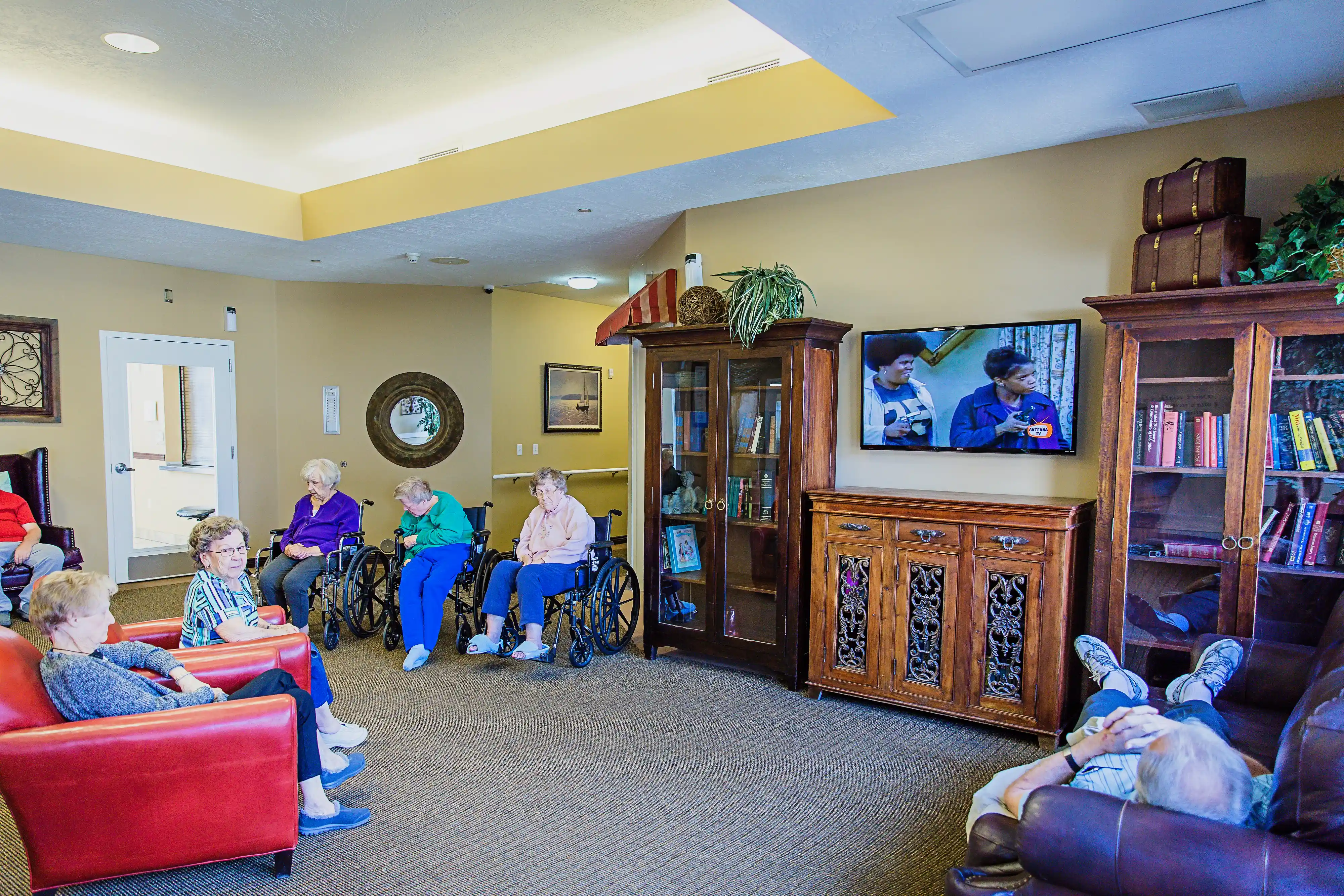 image of a living room with seniors watching tv from couches and wheel chairs