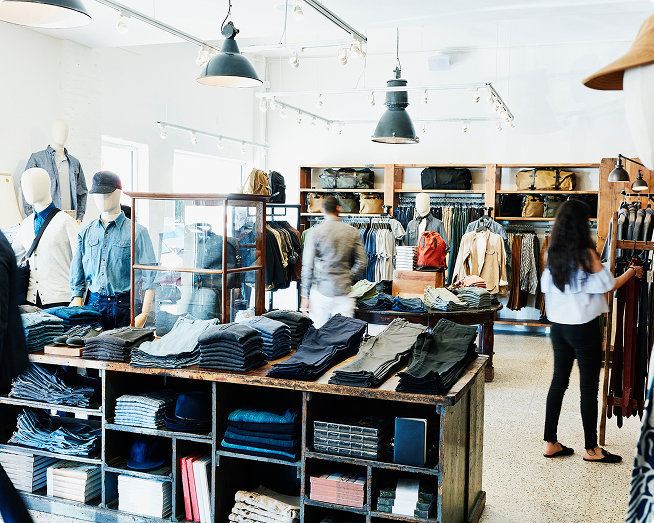 Interior of a modern clothing store with folded jeans and apparel on display.