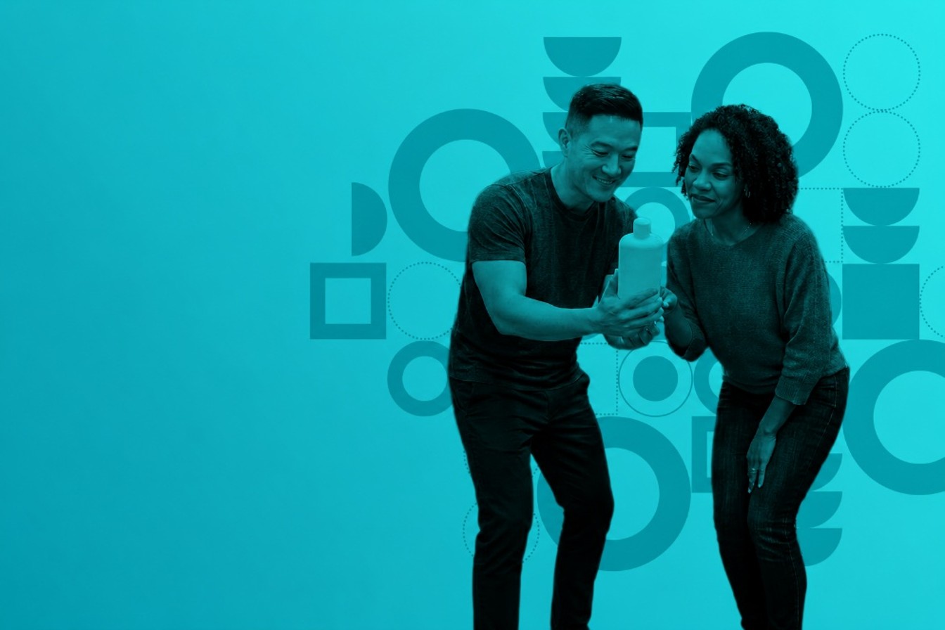 Man and woman looking at a white bottle together, standing against a teal background with abstract geometric shapes.
