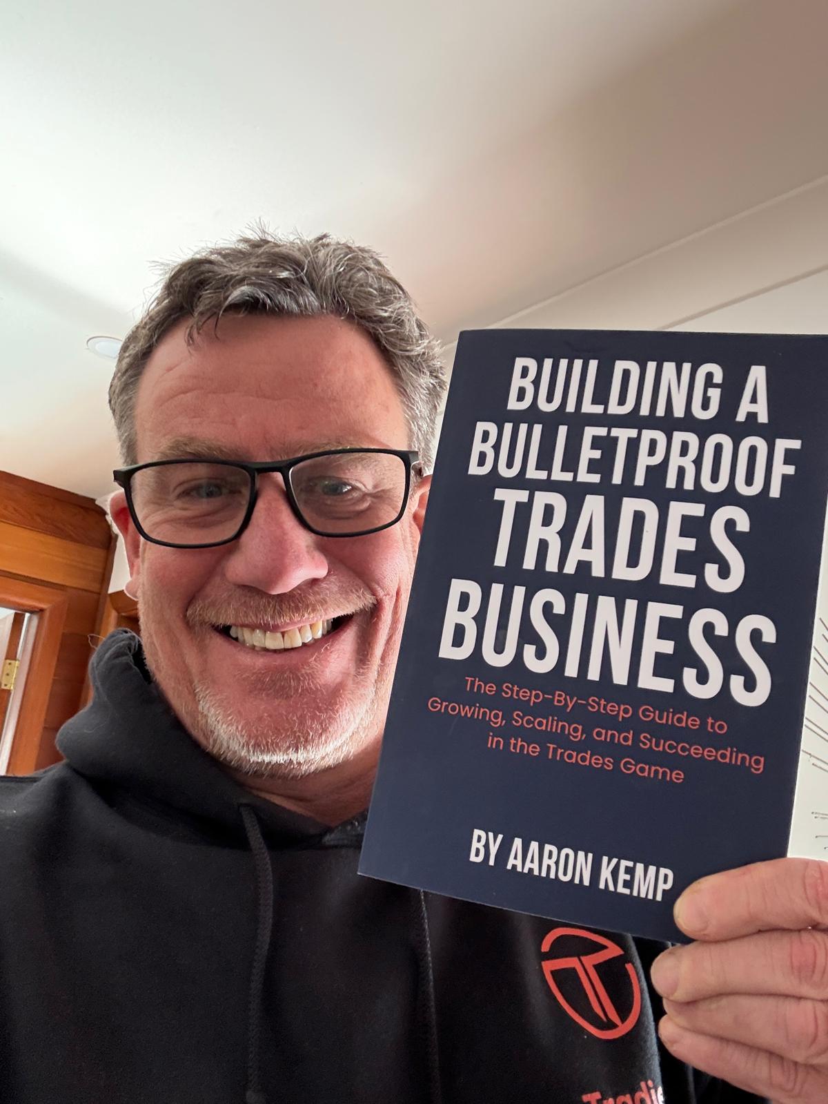 Aaron Kemp holding his book Building a Bulletproof Trades Business