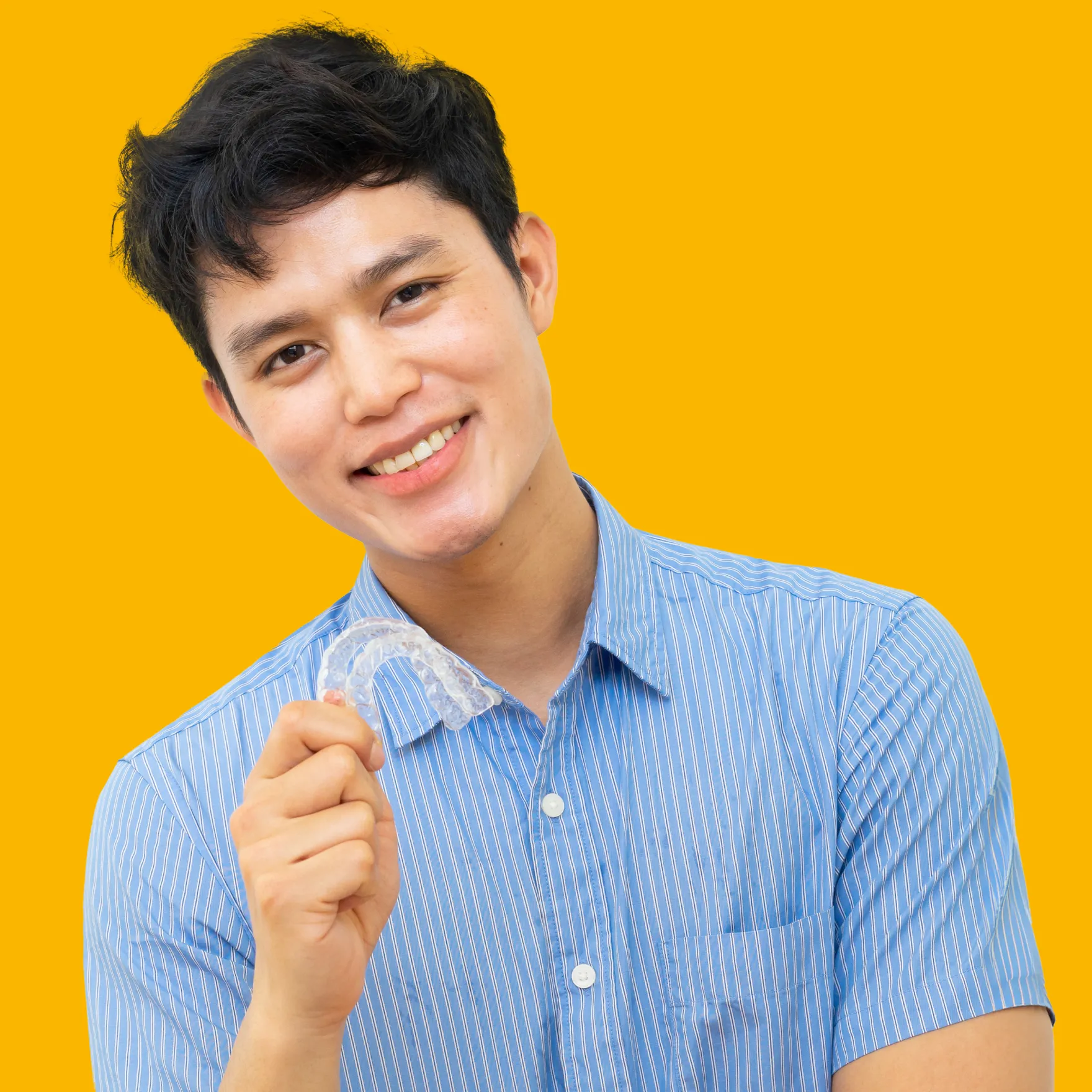 Invisalign in New York, NY | young man smiling holding an Invisalign Tray