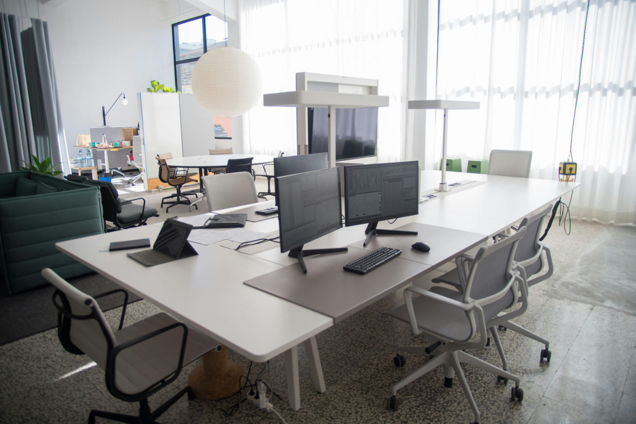 Modern office workspace with dual monitors, white desk, and large windows