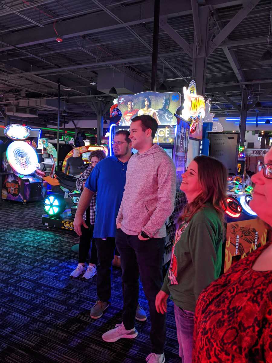 People standing near arcade games with colorful lights and screens