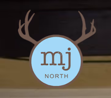 Logo with lowercase letters 'mj' and word 'NORTH' below inside a blue circle with brown antlers on a dark background.