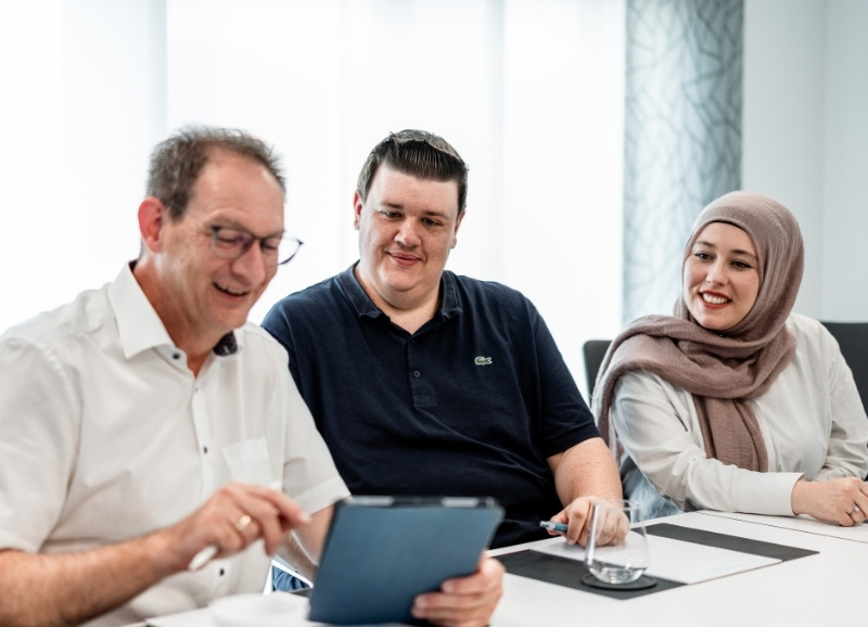 Christoph Remy, Partner der Steuerberatung remy · kaufmann · schöneberg in Ransbach-Baumbach, sitzt mit zwei Mitarbeitern am Besprechungstisch und arbeitet mit einem Tablet.