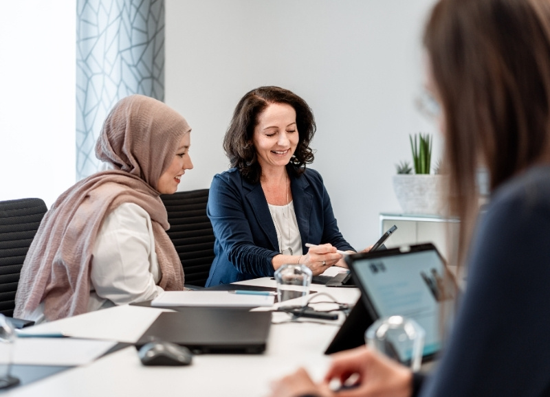 Tugba Tasci Steuerfachangestellte der Steuerberatung remy · kaufmann · schöneberg in Ransbach-Baumbach im Gespräch mit einer Kollegin am Besprechungstisch.