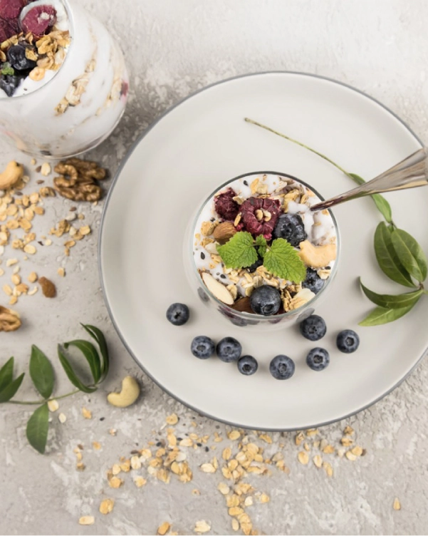 Un bol delicios de iaurt cu granola, fructe de pădure și nuci, gata de a fi savurat cu o lingură.