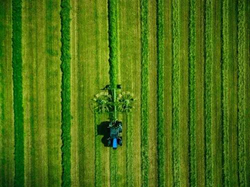 Aerial view of tractor moving on grass - green field