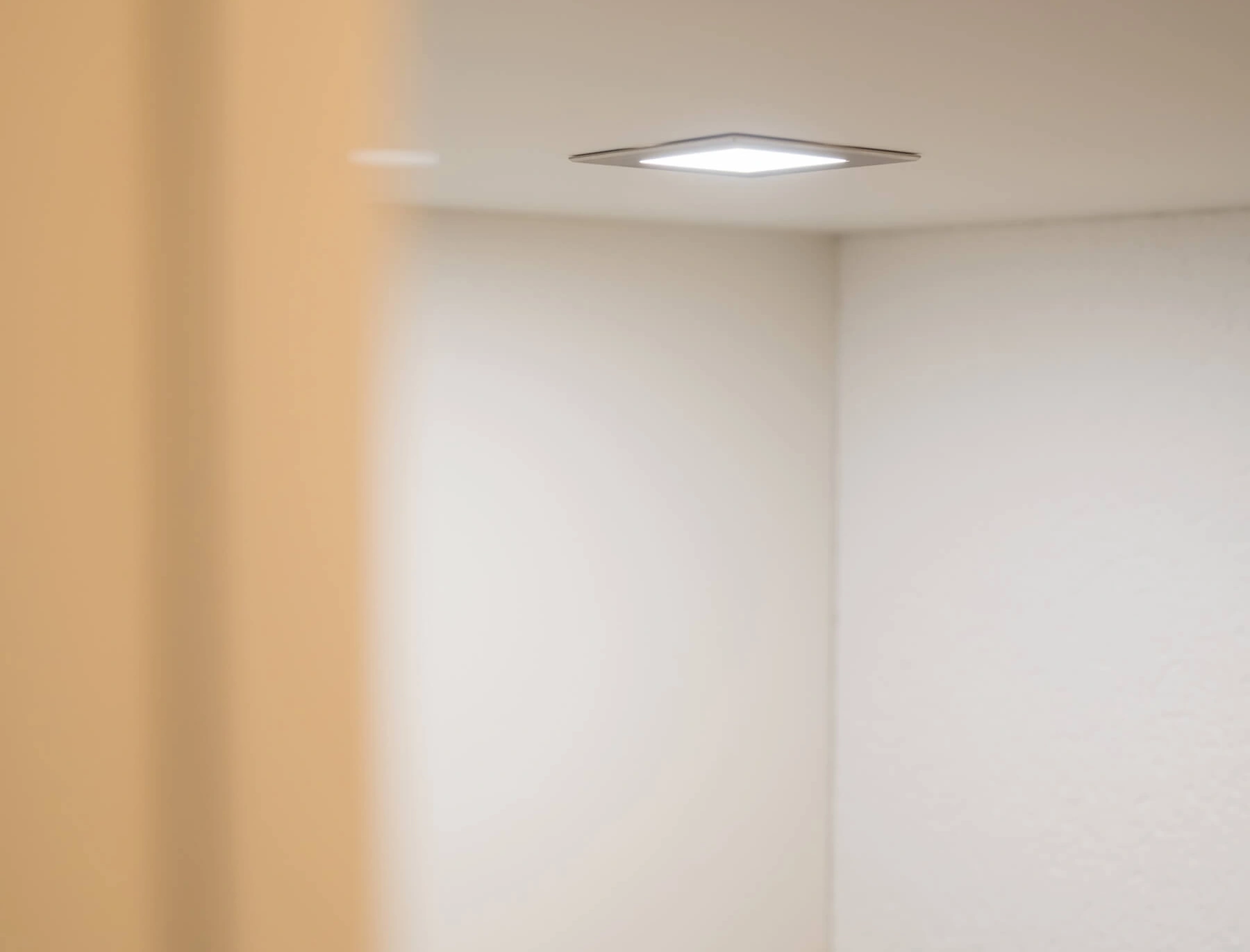 Quadratische Deckenleuchte in minimalistischem, hellem Raum mit sanften Farben