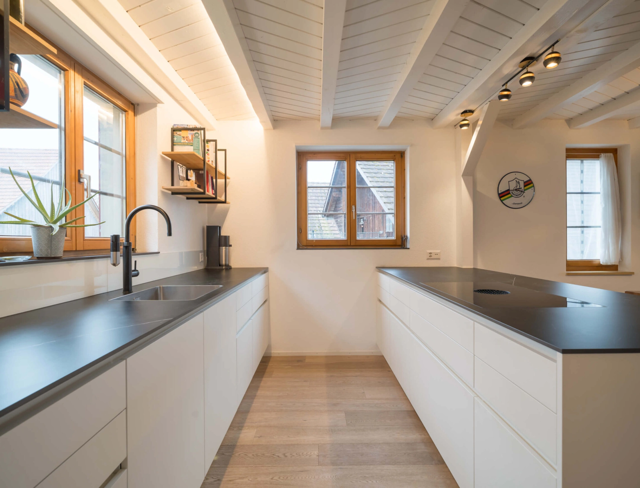 Moderne, weiße Küche mit Holzfenstern und schwarzer Arbeitsplatte