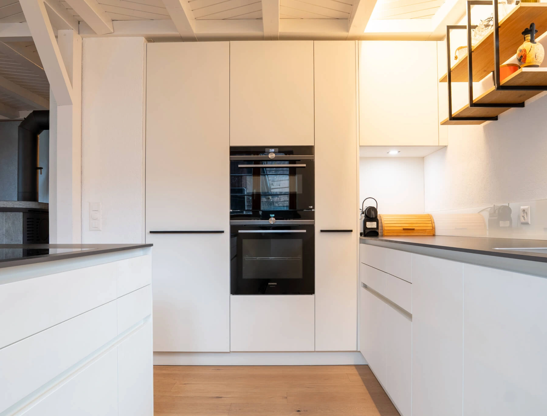 Moderne weiße Küche mit eingebauten Geräten und Holzboden