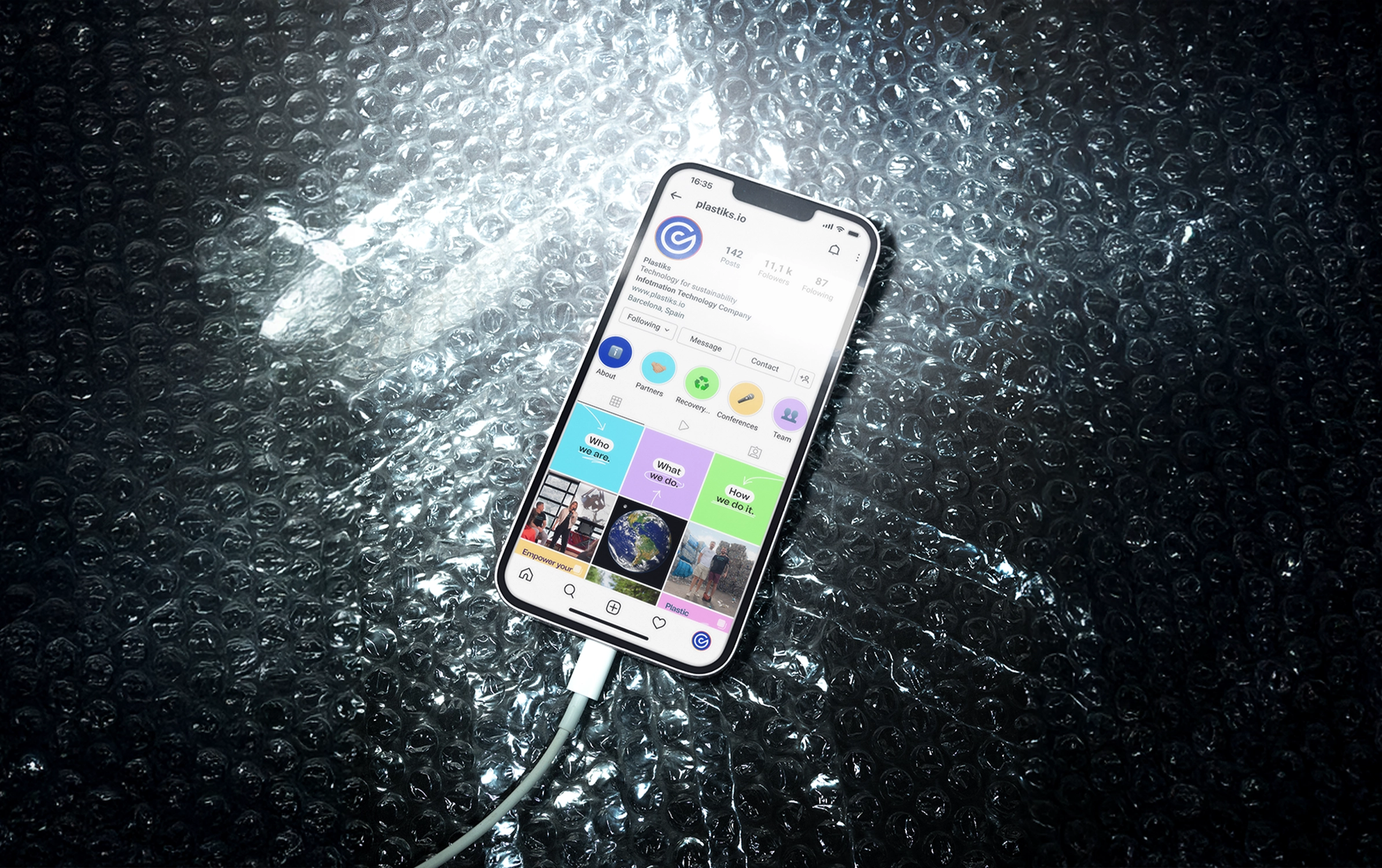 Smartphone displaying the Instagram profile of plastiks.io on reflective bubble wrap background.
