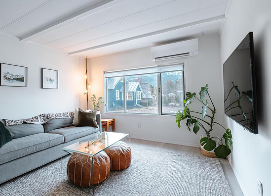 cozy living room featuring a gray sectional sofa, glass coffee table, potted plants, and a large window with scenic outdoor views