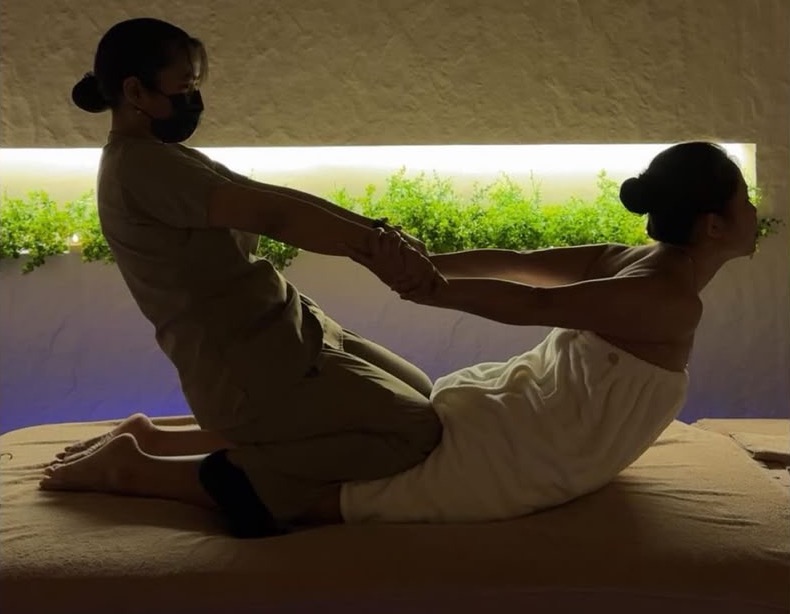 Therapist performing an assisted back-extension stretch during a traditional Thai massage at Escape 8 Spa.