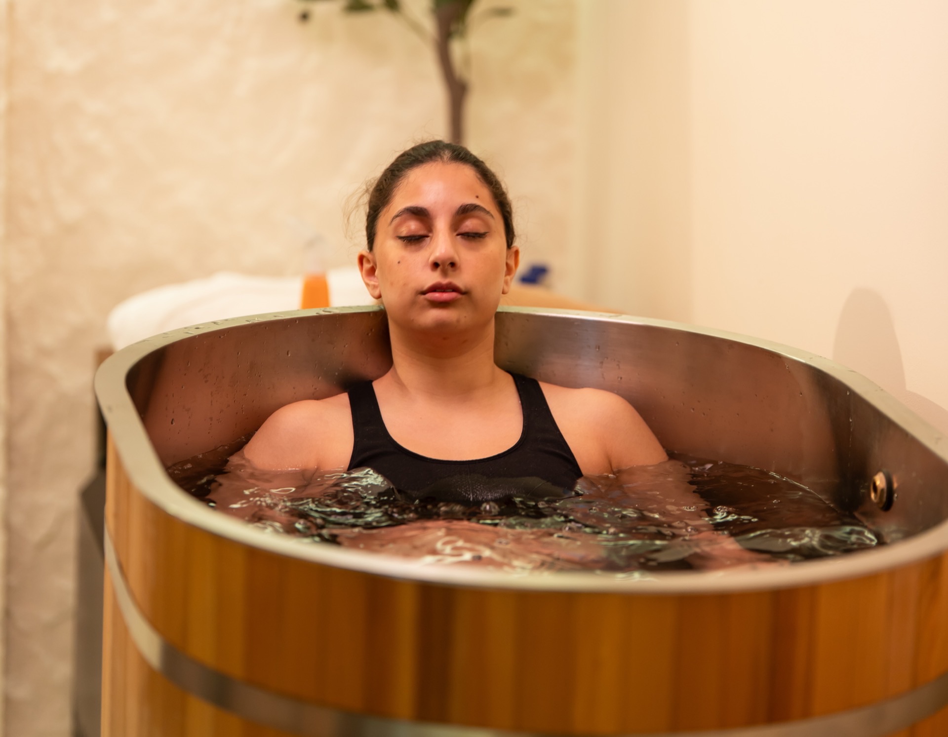 Guest sitting in the wooden cold plunge tub during a contrast therapy session at Escape 8 Spa.