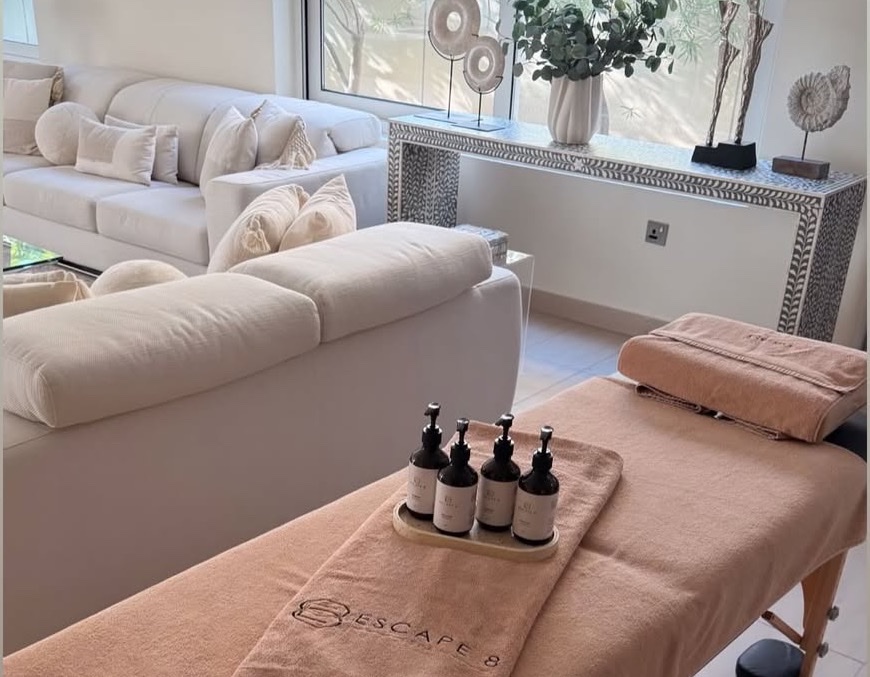 Escape 8 Spa massage table set up with branded towels and treatment oils in a client's living room for a home service appointment.