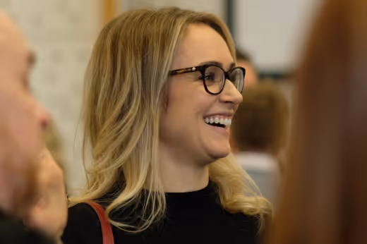 A woman laughs and smiles while chatting with colleagues at a conference