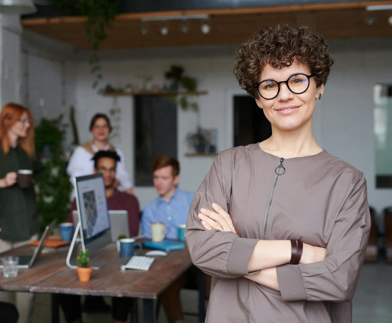 A team leader standing in front of a group of people in a modern office.