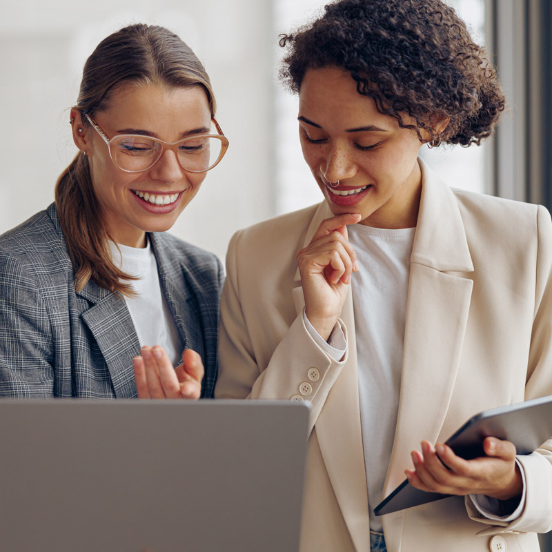 Professional female managers in a modern office using a laptop and digital tablet for work