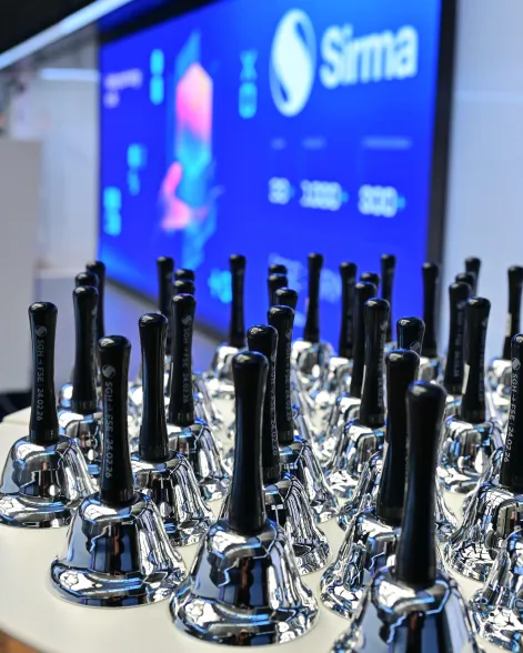 Dozens of silver bells lined up on a table in preparation for the celebration ceremony of the dual listing of Sirma Group at the Frankfurt Stock Exchange