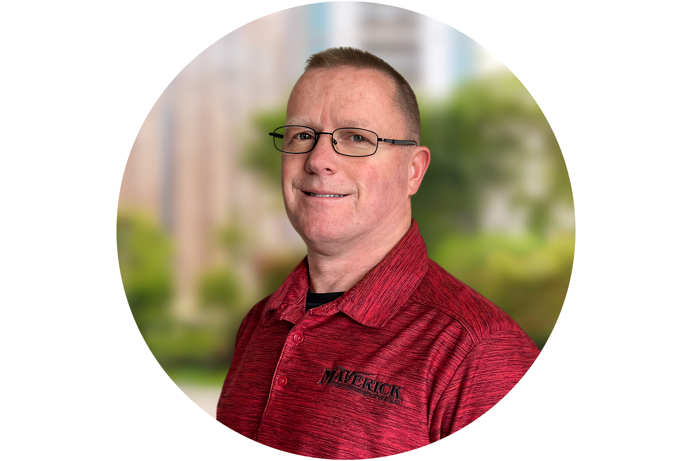 Smiling man wearing glasses and a red Maverick branded polo shirt with a blurred outdoor background.