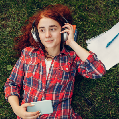 Person listening to phone, laying in the grass