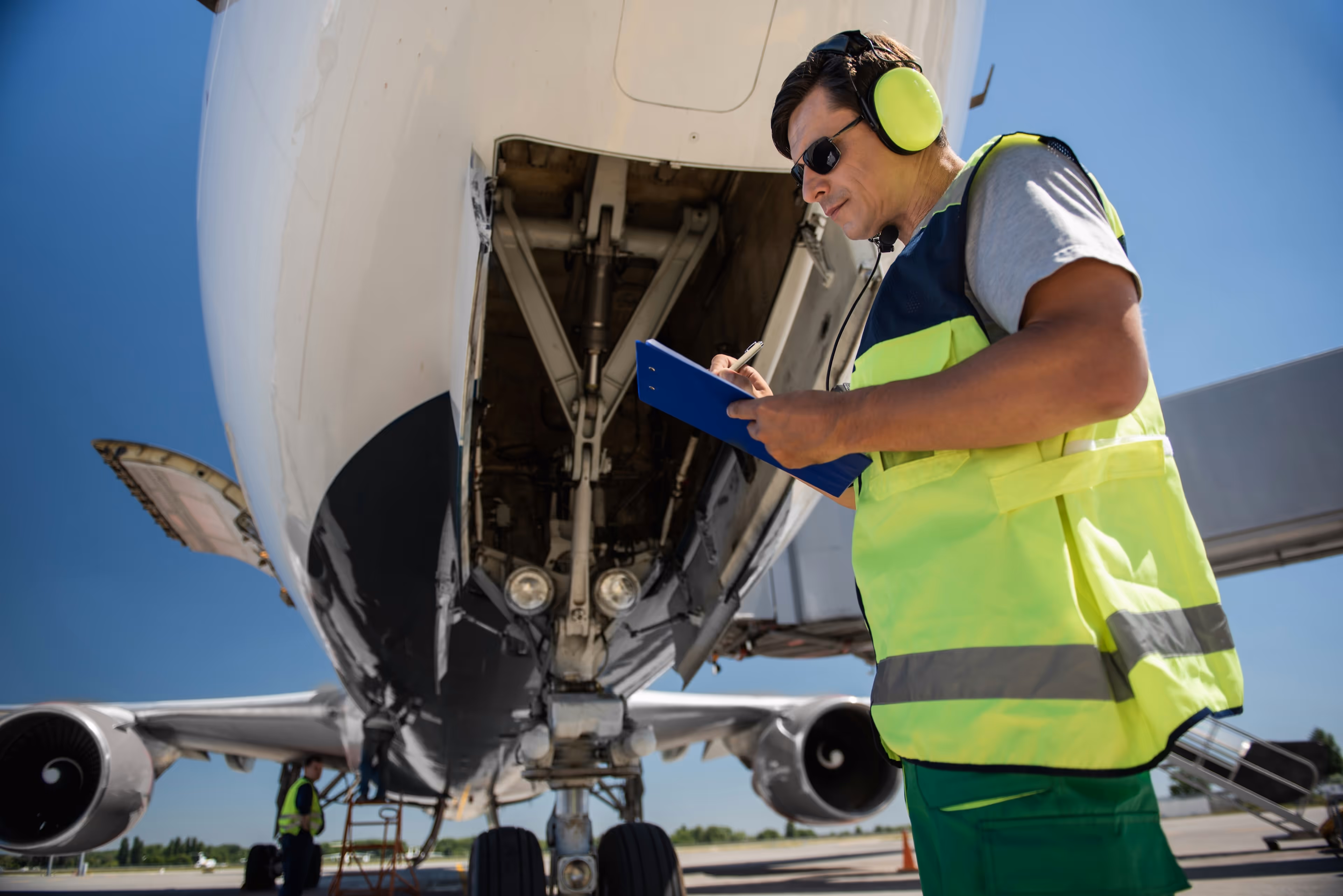 Ground staff performing inspection at the nose wheel of an airplane.