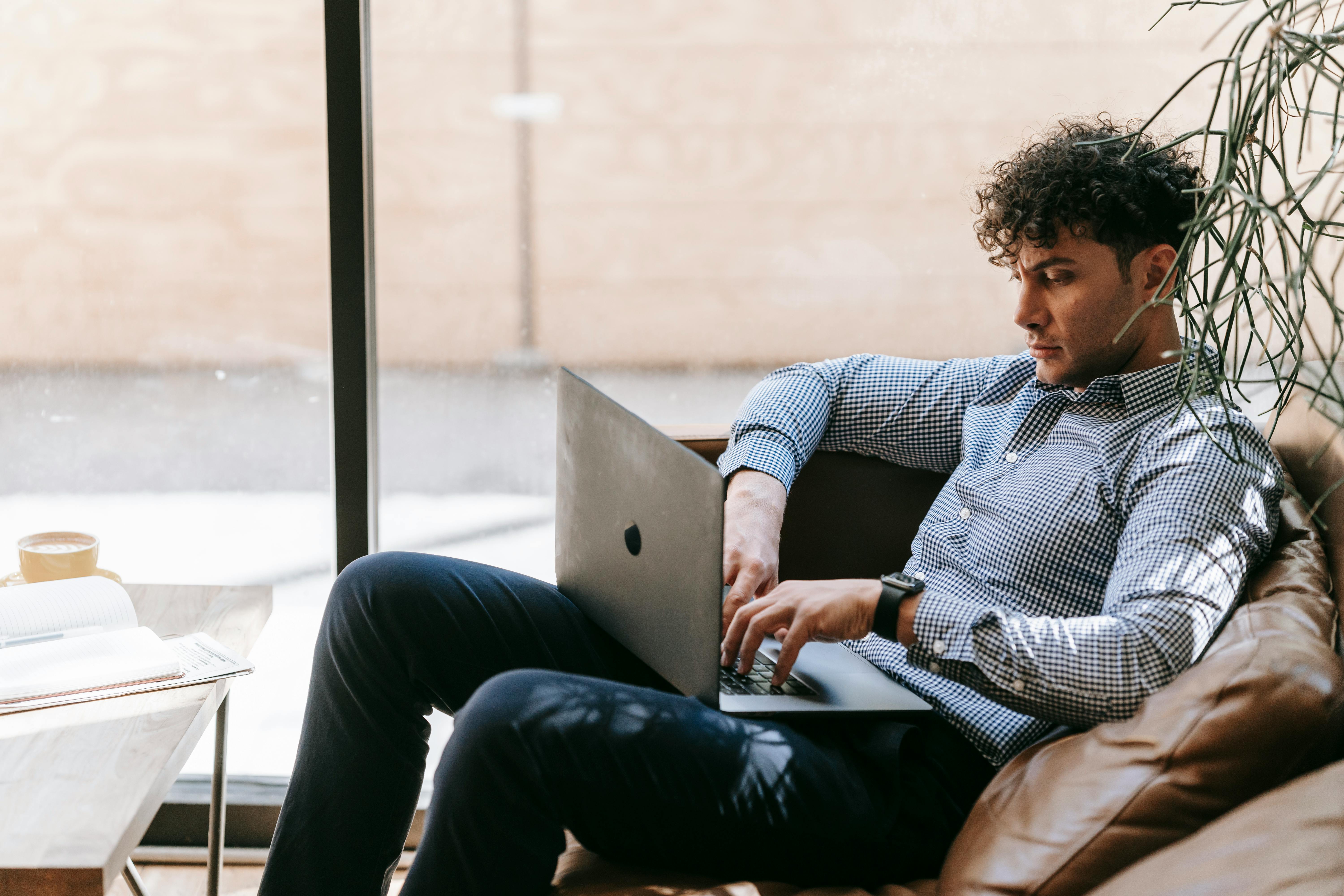 a man sitting down on a chair with his laptop open on his lap