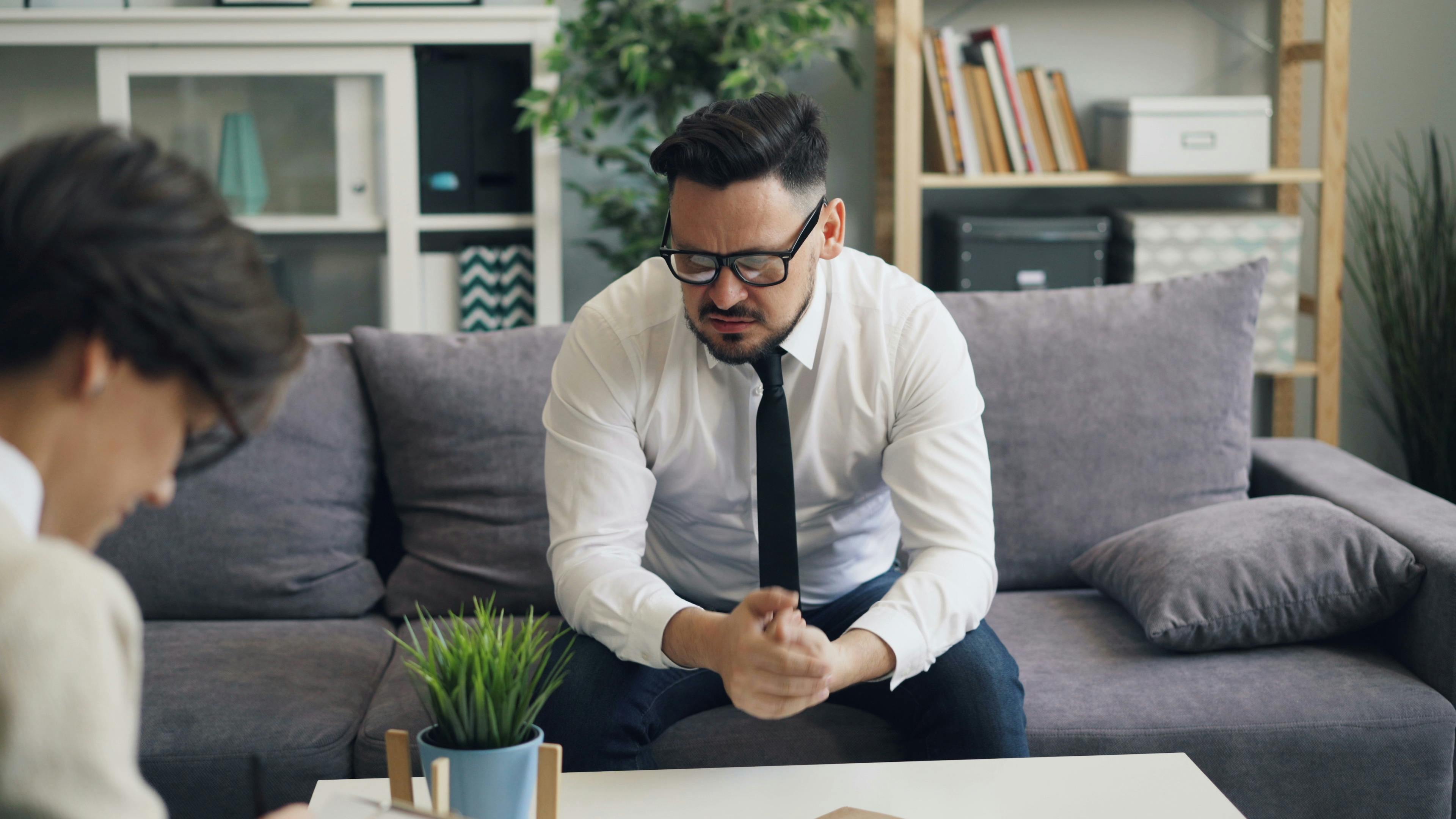 a man sitting on a couch talking to a therapist