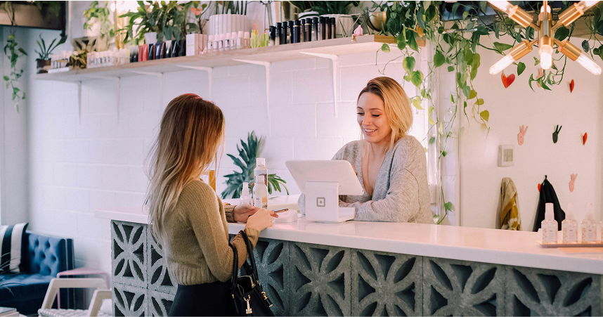 Small business owner smiling at checkout with a customer using Worthify loyalty program to boost repeat visits.