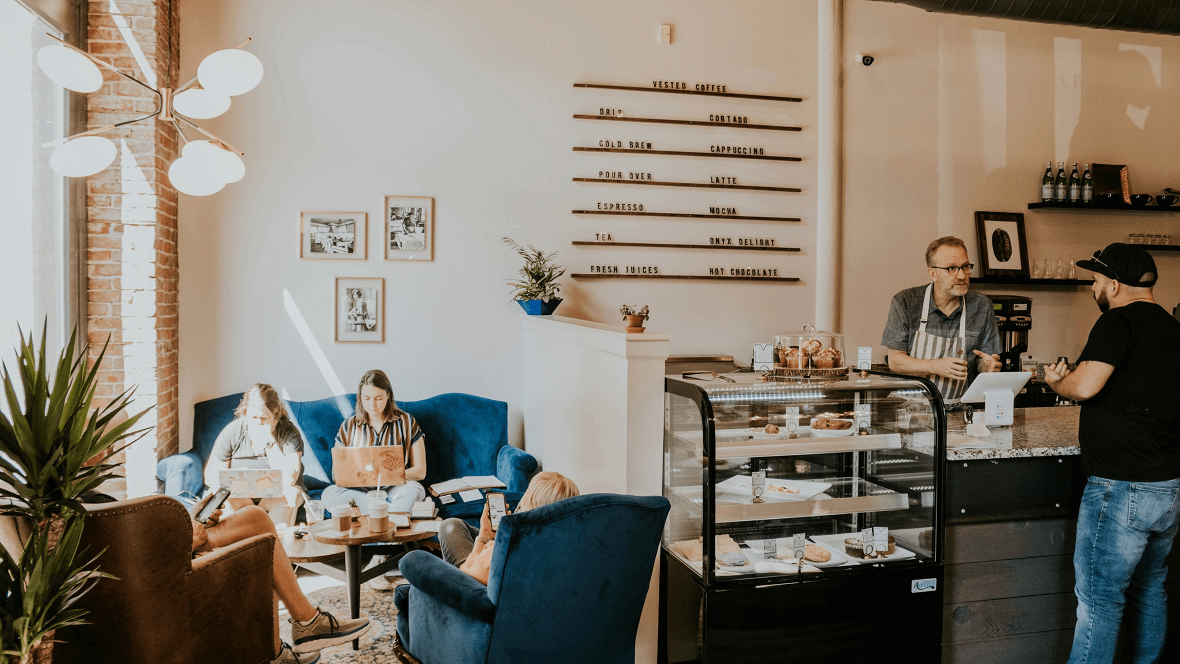 Cozy café with customers working and relaxing while a barista serves at the counter — representing Worthify’s mission to help local businesses thrive.