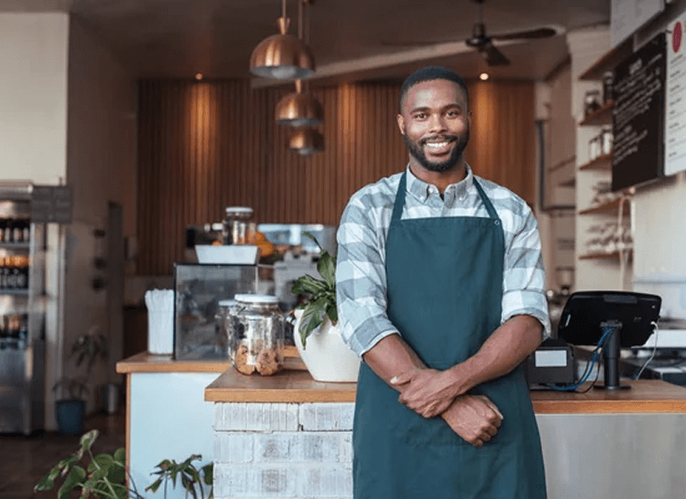 Small business owner standing proudly inside his café, symbolizing Worthify’s mission to empower local businesses with simple loyalty tools.